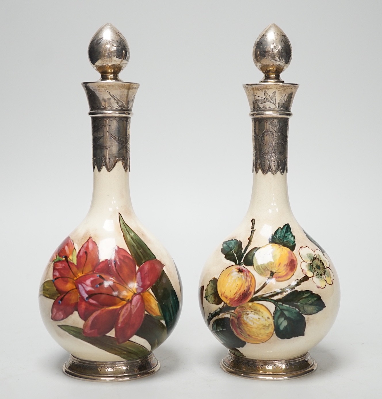 A pair of Victorian silver mounted floral painted earthenware bottle vases. 21cm high